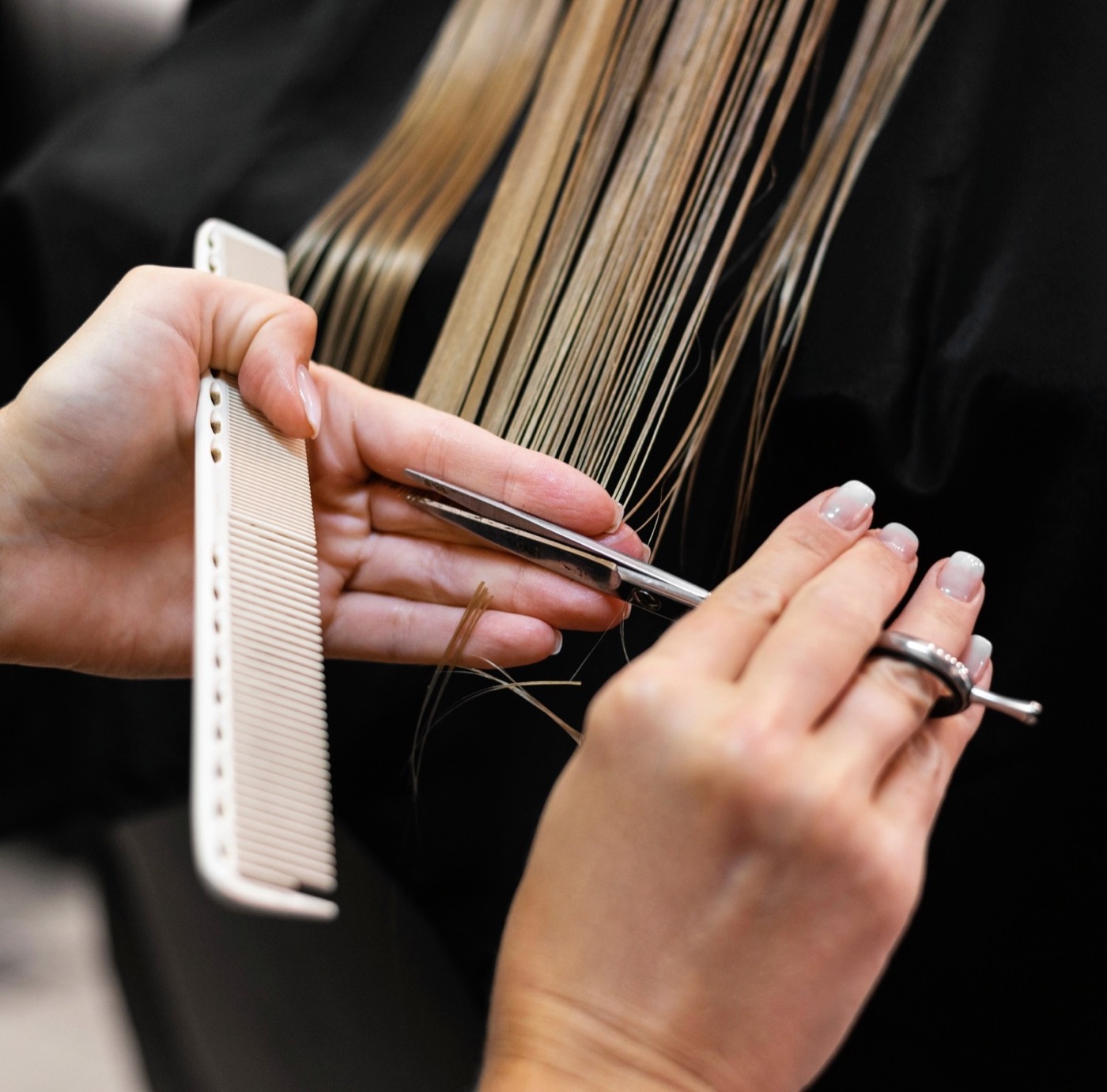 A stylist cutting hair with comb and scissors
